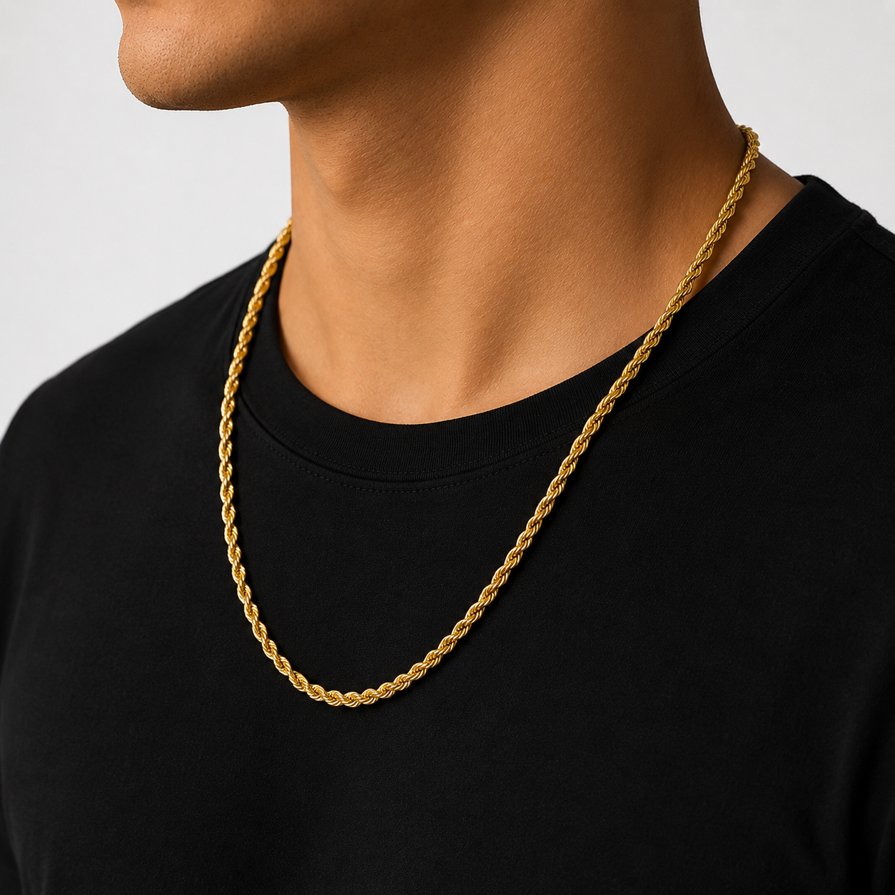 Gold chain necklace on a person wearing a black shirt against a neutral background