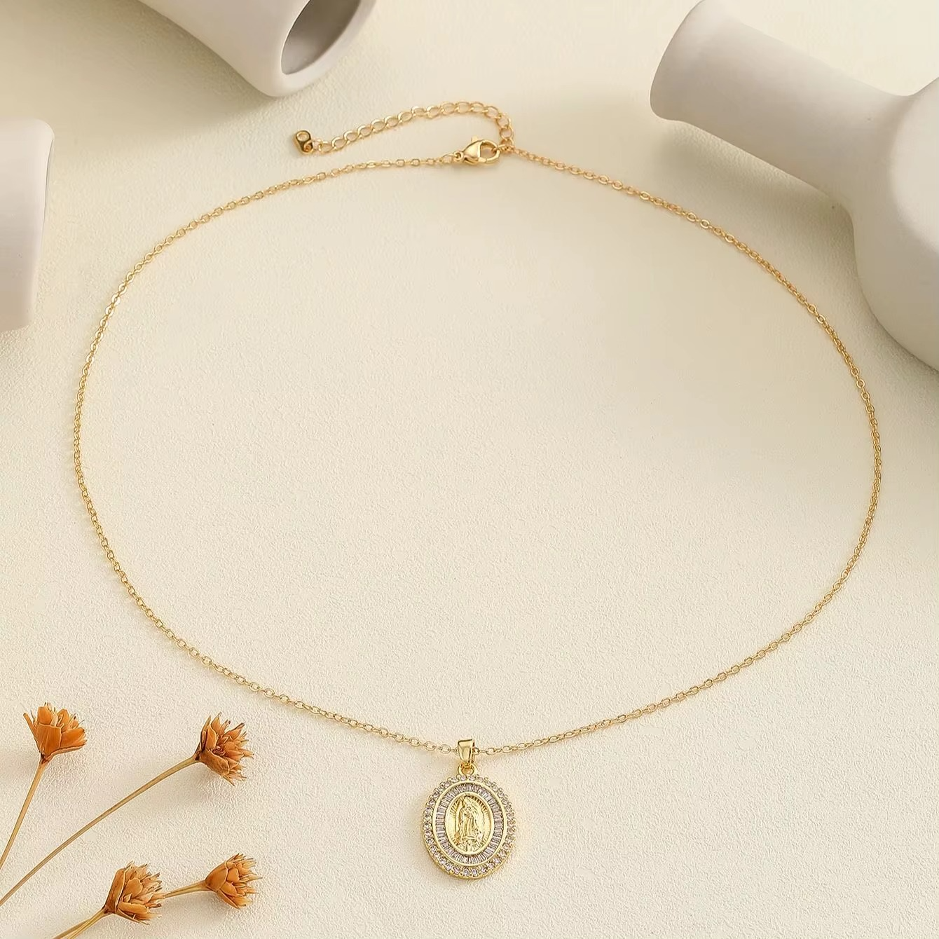 Gold necklace with a pendant on a light beige background