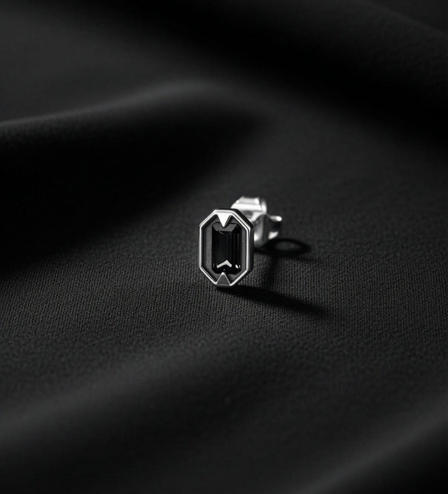 Silver earring on black fabric