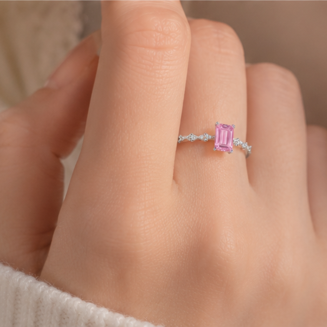 Pink gemstone ring on a person's finger with a neutral background